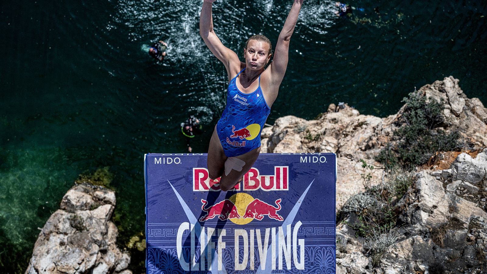 action shot of a person back flipping in to the ocean below from a diving board